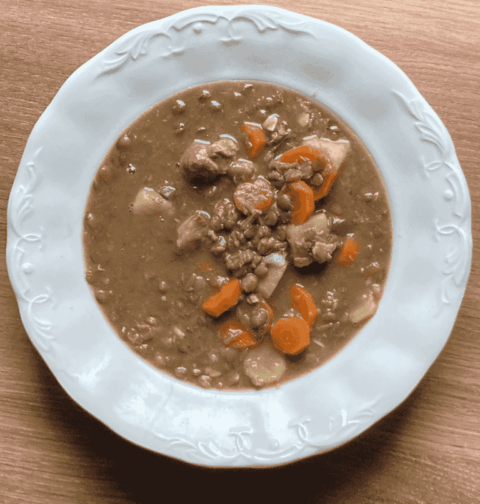 Tányérban tálalt, sűrű lencsegulyás sertéshússal és sárgarépával. Kiadós magyar egytálétel.