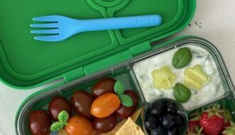 Színes uzsonna meal prep összeállítás gyerekeknek rekeszes uzsonnásdobozban zöldségekkel, gyümölcsökkel és teljes kiőrlésű falatokkal.