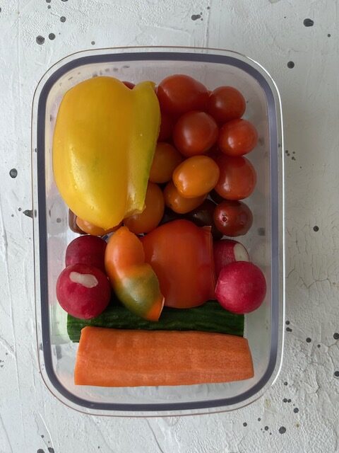 Előkészített, friss zöldségek egy dobozban, amelyek az uzsonna meal prep alapját képezik a héten.